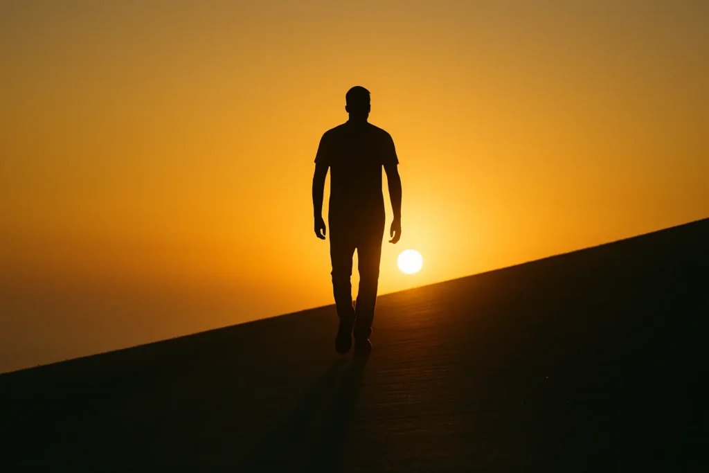 Silhouette of a man walking on an incline path at sunrise with long shadow, symbolizing daily discipline, recovery, and resilience in Mario McKenzie’s 90-day keto transformation.