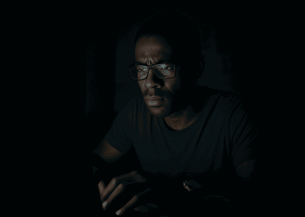 A man working late into the night by the glow of a computer screen, symbolizing sacrifice and the lonely grind behind letting go of a failed startup.